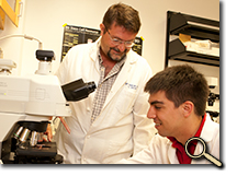 Professor and student scholar conducting cellular research in lab photo